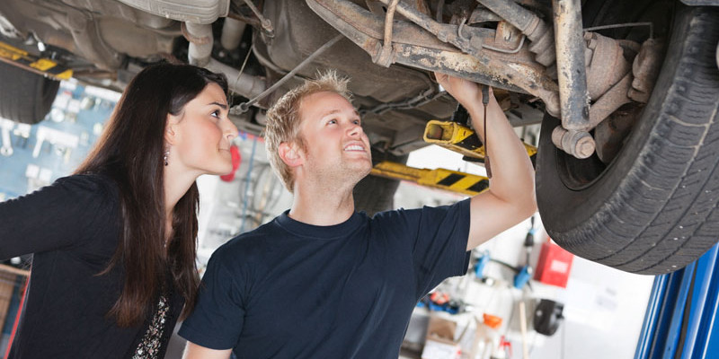 Woman and mechanic looking at car repairs